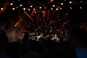 Photographie de concert à Asnières, musiciens sur scène devant un écran LED dynamique, reportage événementiel de spectacle en basse lumière.