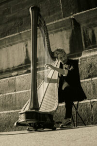 un musicien jouant de la harpe devant un mur en pierre ancienne à Paris.