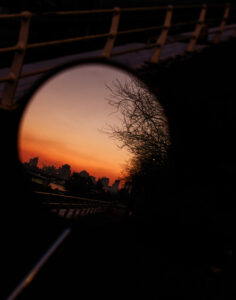 Reflet de la skyline de La Défense au coucher du soleil dans le miroir circulaire d'un rétroviseur.