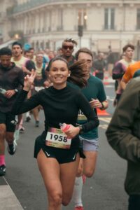 Photographie de reportage sportif semi-marathon de Paris, coureuse souriante en plein effort, style lifestyle urbain.