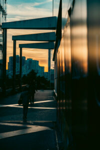 Silhouette d'un passant marchant sur une esplanade moderne à La Défense sous la lumière dorée d'un coucher de soleil.