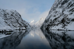 Cette image capture l'immensité et la verticalité des falaises du Trollfjord. Le contraste entre le sillage du bateau et la surface lisse du fjord souligne la tranquillité de ce lieu sauvage.