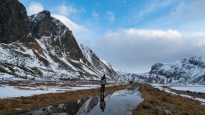 Reflet des montagnes enneigées et d'un homme à Unstad, dans les Lofoten