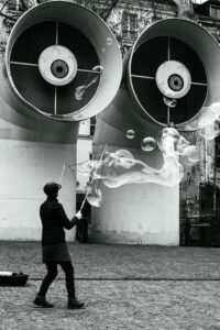 Une personne faisant des bulles de savon géantes devant les bouches d'aération en forme d'yeux du Centre Pompidou à Paris.