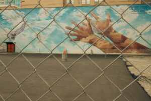 Murale artistique du Calgary Urban Project Society représentant une colombe blanche et des mains tendues vers le ciel derrière un grillage.