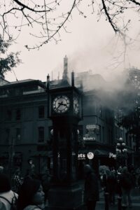 Photographie en noir et blanc de l'horloge à vapeur de Gastown (Steam Clock) dégageant de la buée dans une rue historique de Vancouver.