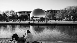 La Géode au Parc de la Villette à Paris, avec des passants se relaxant au bord du canal de l'Ourcq.