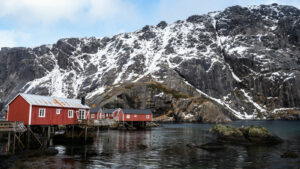 Voici les propositions pour optimiser le SEO de cette image de Nusfjord dans votre interface WordPress : Texte alternatif (Alt Text) Cabanes de pêcheurs rorbuer rouges traditionnelles à Nusfjord, entourées de falaises enneigées dans les îles Lofoten en Norvège.