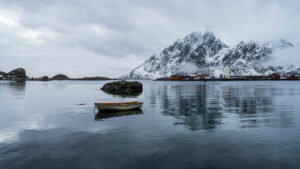 Petite barque de pêcheur au bord d'un fjord dans les Lofoten avec reflet dans l'eau.