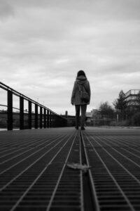 Vue en contre-plongée et noir et blanc d'un marcheur solitaire de dos sur une passerelle métallique à Nantes.